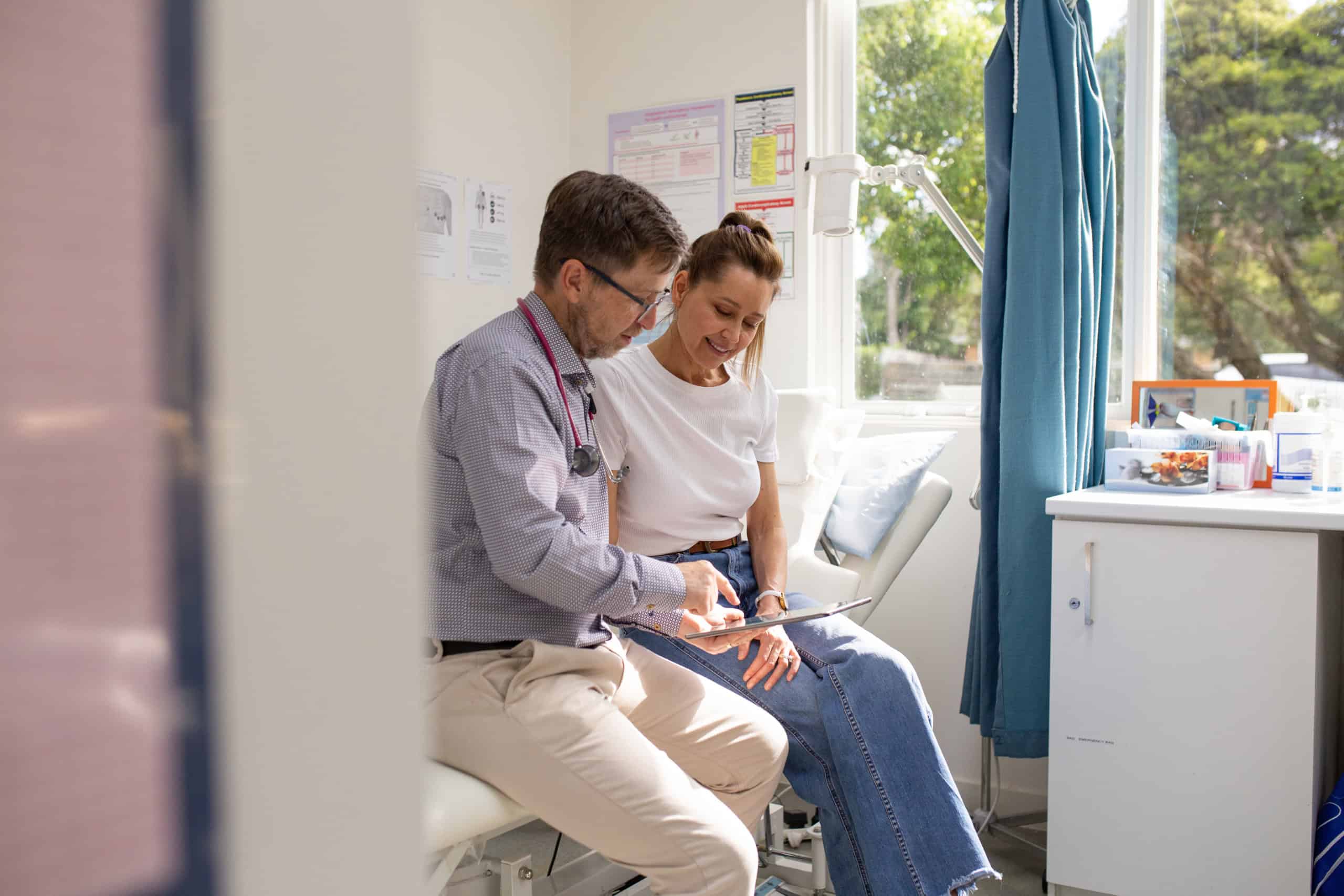 Male doctor holding a tablet and talking to a female patient in the clinic