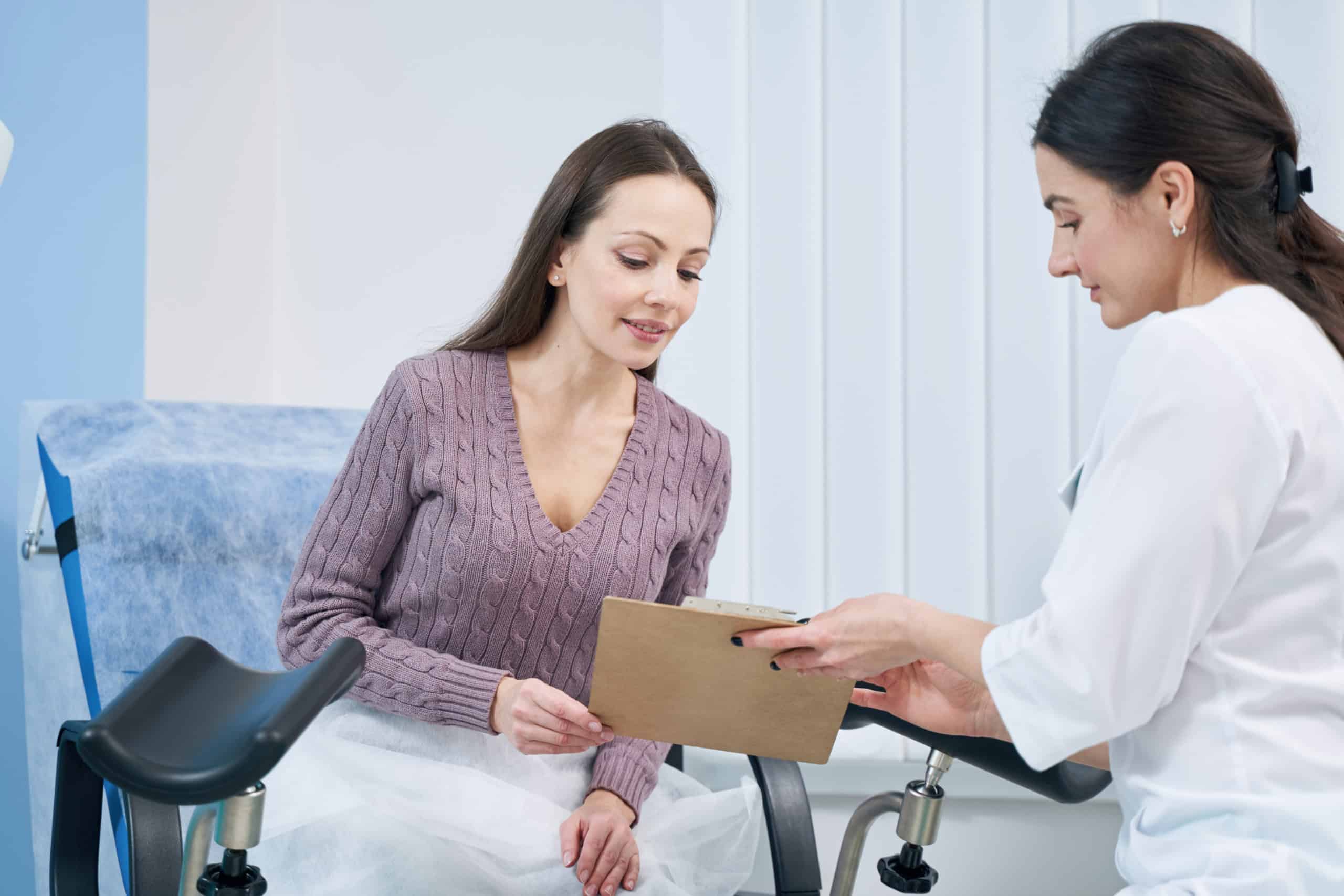 Focused young Caucasian female patient looking at informed consent form presented by gynecologist